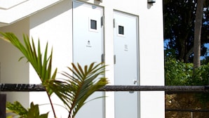 Un edificio con dos puertas blancas, una señalizada para duchas y la otra para baños.