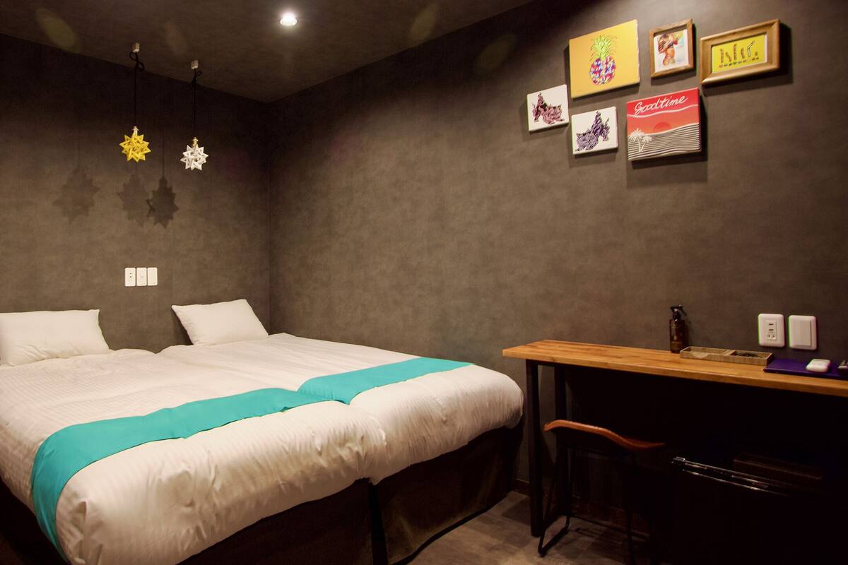 A hotel room with a bed, a desk, a chair, and a small table.