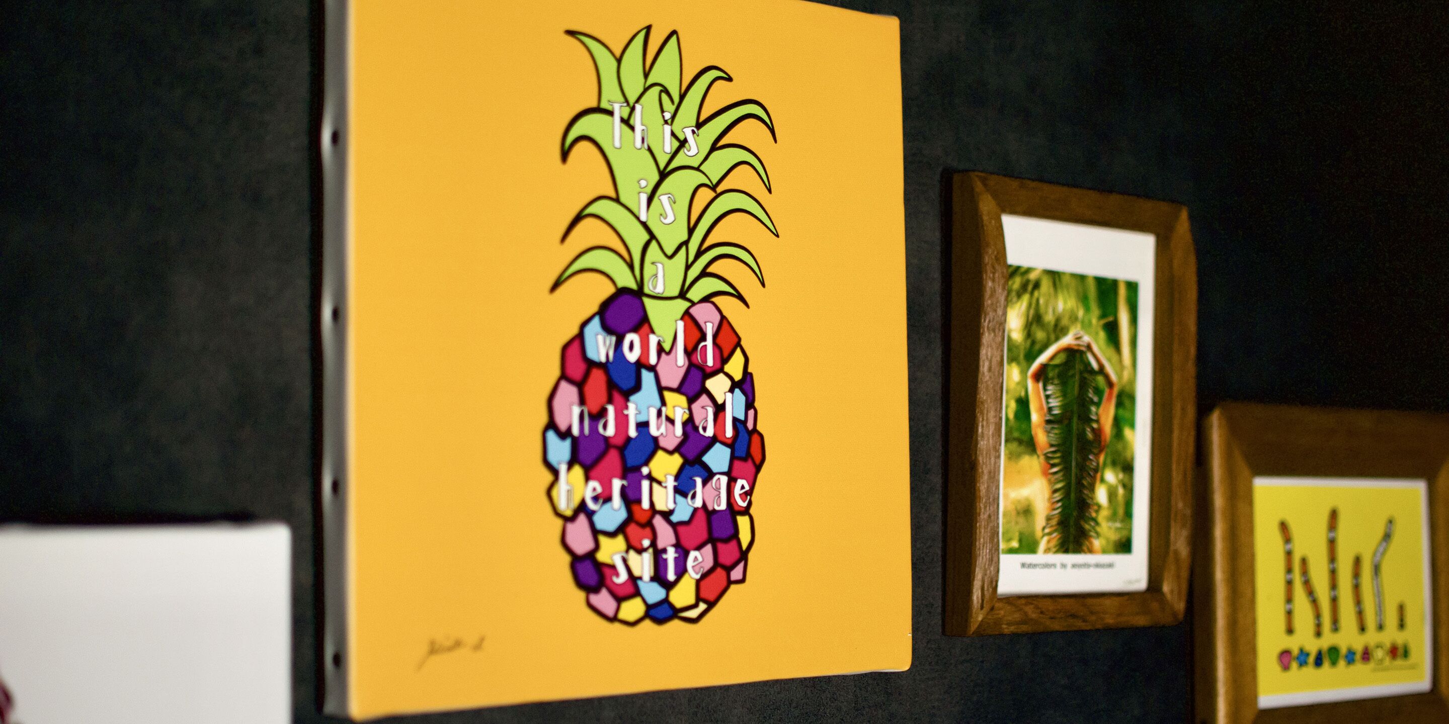 Una obra de arte enmarco con una piña colorida sobre fondo amarillo.