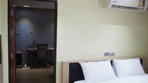 Een hotelkamer met een bed, een bureau en een airconditioning.