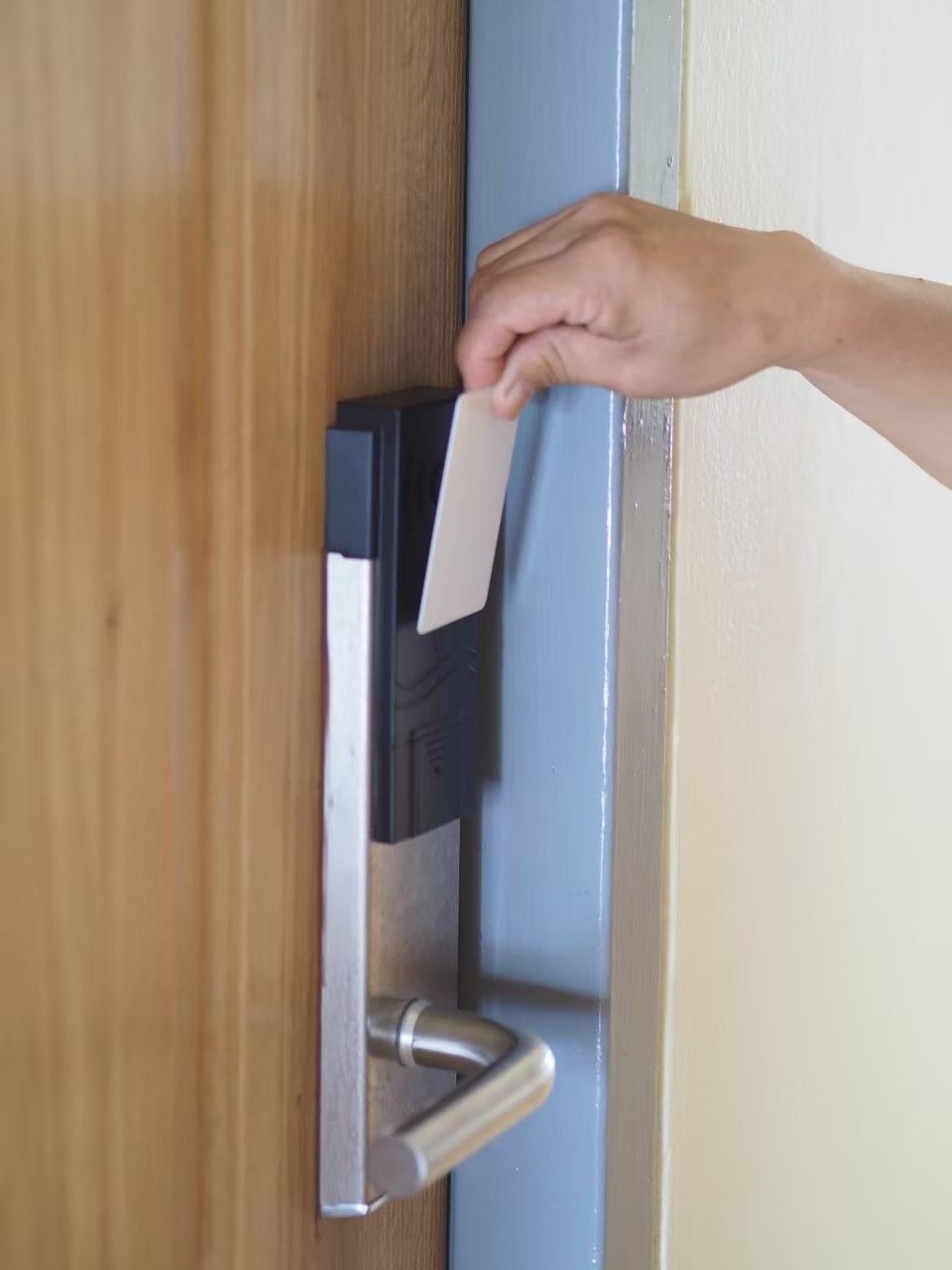 Une main insérant une carte dans un lecteur de carte, probablement pour accéder à une pièce ou effectuer un paiement.