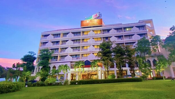 Een hotel met meerdere verdiepingen en een centrale binnentuin, omringd door weelderige begroeiing en palmbomen.