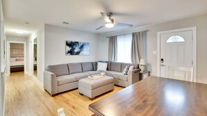 A modern living room with a sectional sofa, a wooden dining table, and a ceiling fan. - Central Austin 6 Bedroom Gem (Austin)