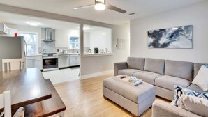 A modern living room with a grey sofa, a wooden dining table, and a ceiling fan. - Central Austin 6 Bedroom Gem (Austin)