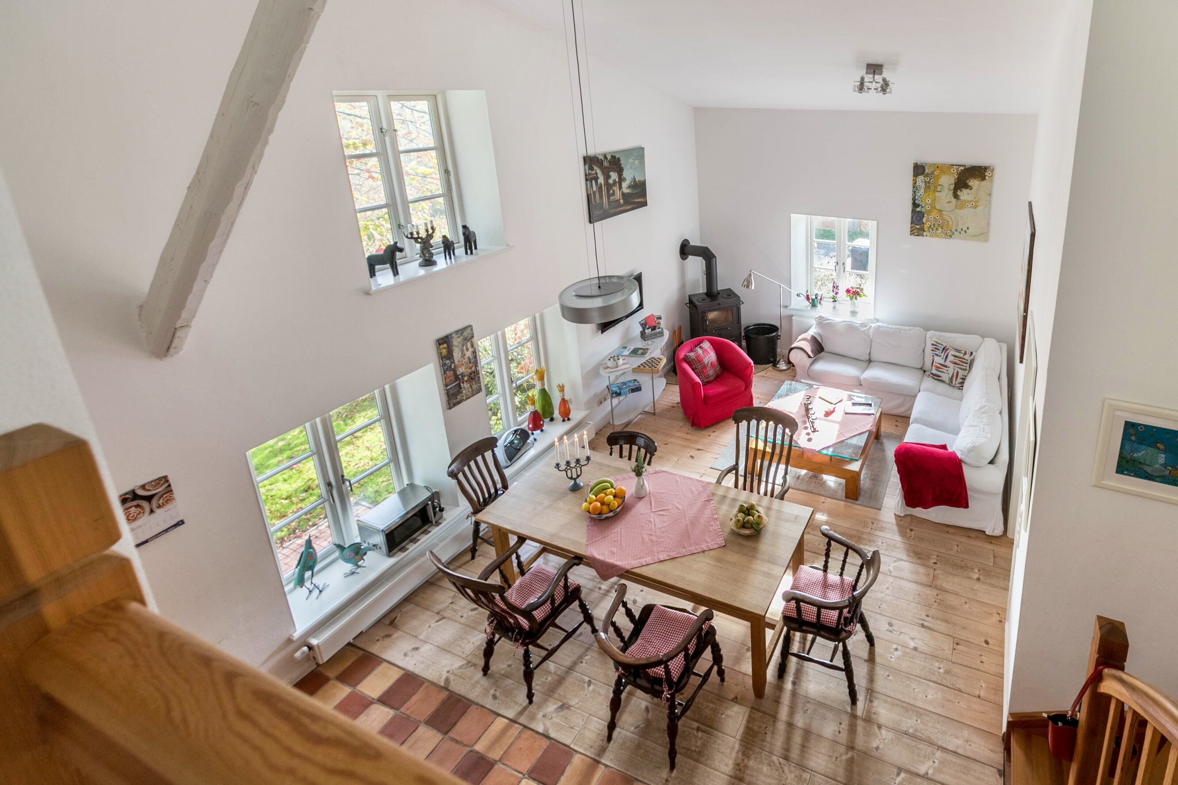 Un vaste espace de vie doté d’un haut plafond, d’une cheminée, d’une table à manger avec des chaises et d’un canapé.