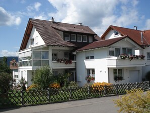 Un bâtiment à deux étages doté de balcons, d’une clôture en bois et de jardinières.