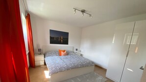 Une chambre à coucher avec un lit, des tables de chevet, une lampe, un tableau et une armoire.