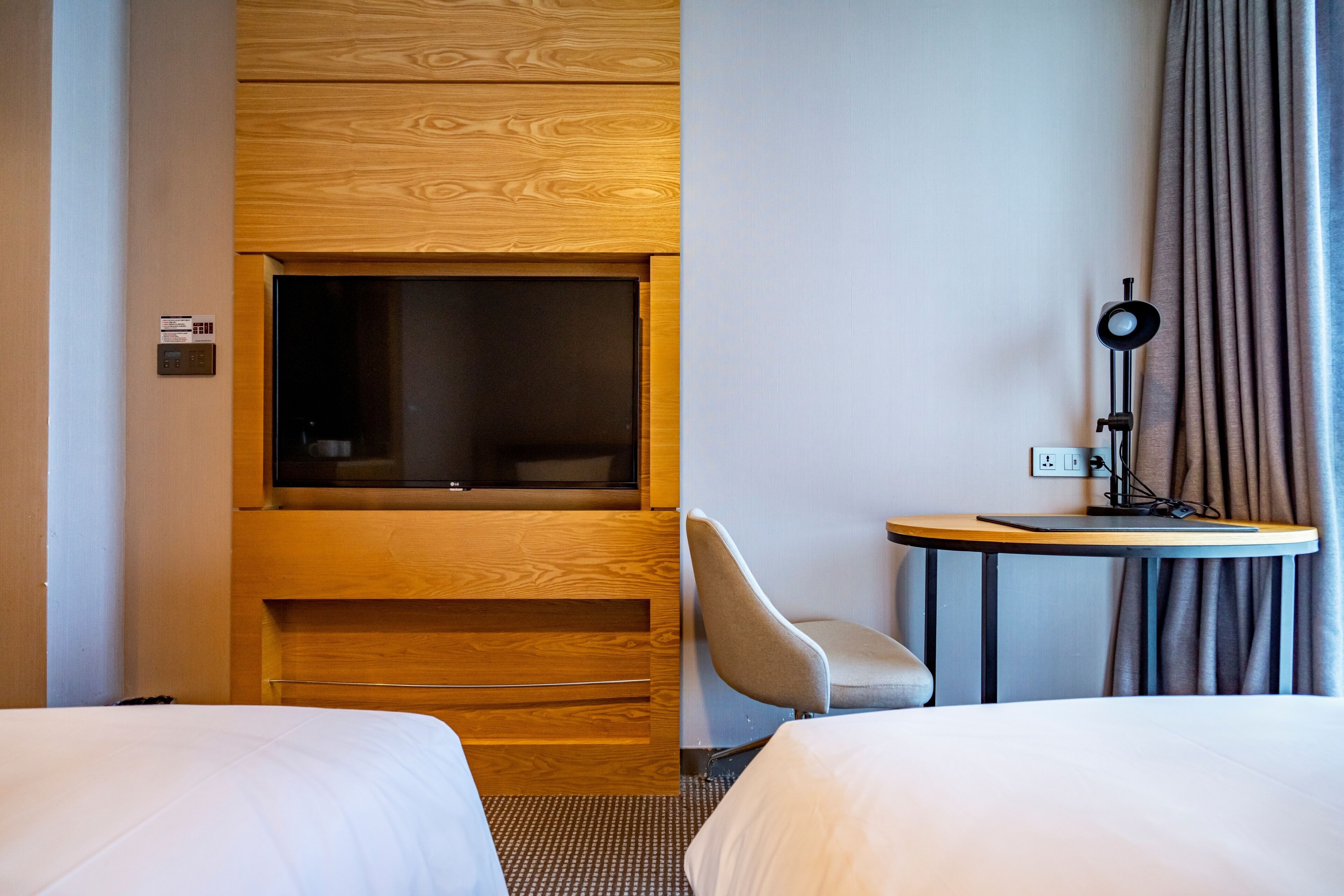 Une chambre d’hôtel avec deux lits, une télévision, un bureau avec une lampe et une chaise.