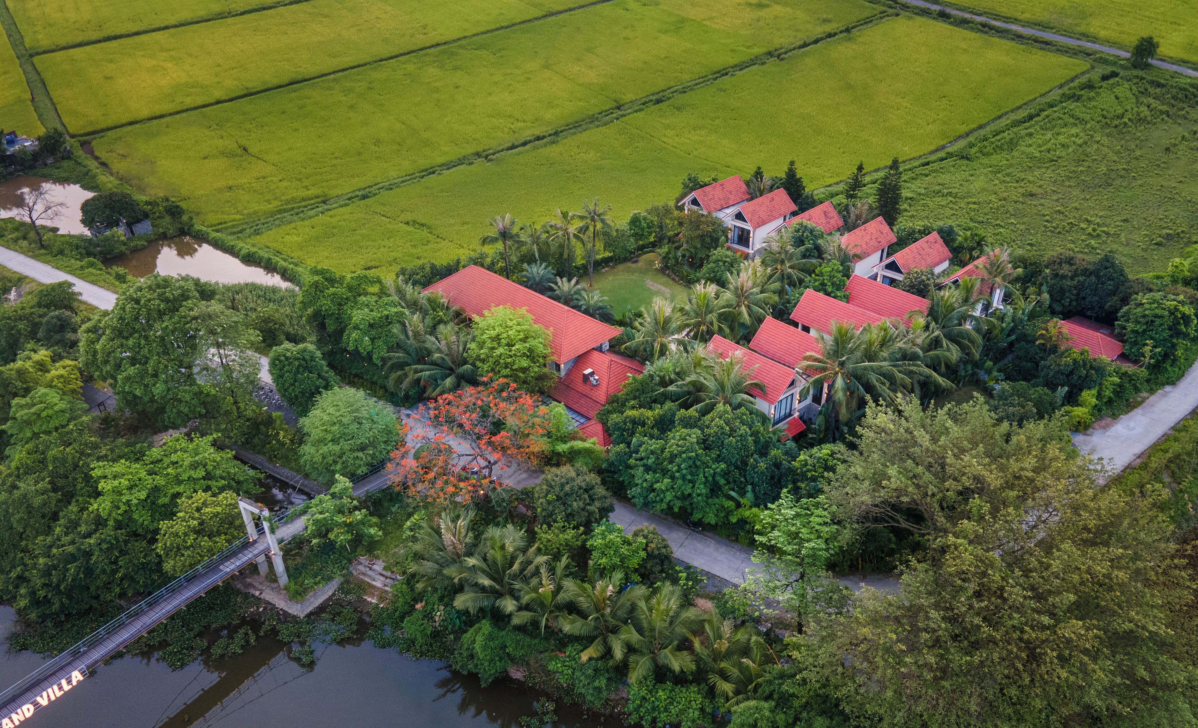 An aerial view of a residential area with multiple houses, a bridge, and surrounding greenery.