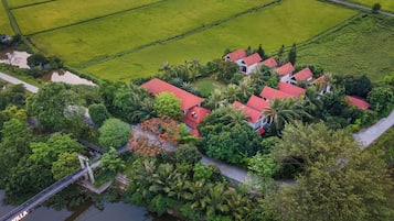 An aerial view of a residential area with multiple houses, a bridge, and surrounding greenery.