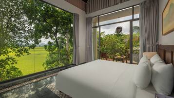 A bedroom with a large window, a bed, and a view of a green landscape.