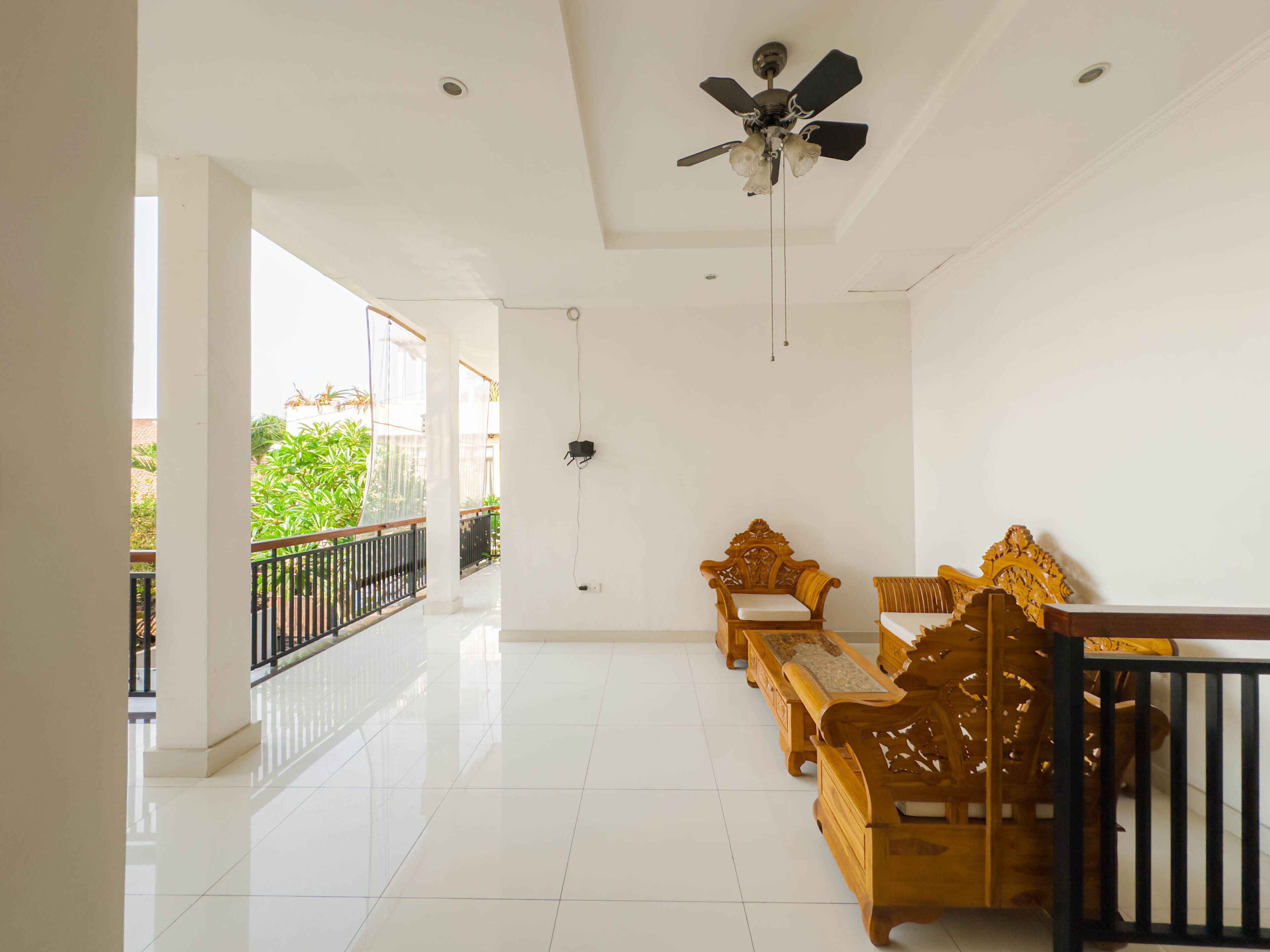 A spacious room with a balcony, a ceiling fan, and wooden furniture.