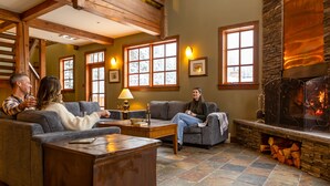 A cozy living room with a fireplace, stone flooring, and wooden beams.