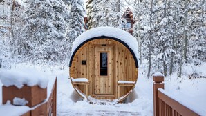 A wooden cabin with a snow-covered entrance and a wooden deck leading to it.