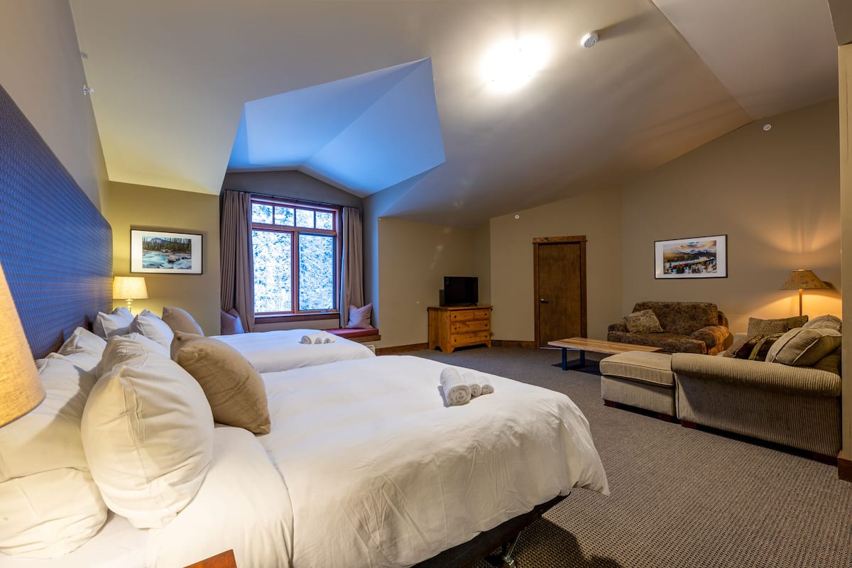 Um quarto espaçoso com uma cama grande, um sofá e uma televisão.