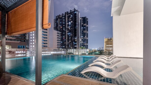 A swimming pool with a view of high-rise buildings at night. - Reizz Residence by Plush (Kuala Lumpur)