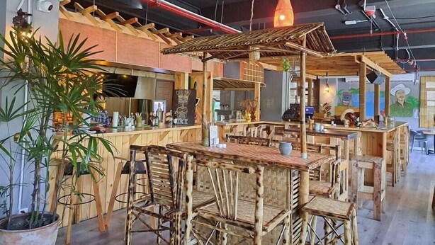 Un área de bar rústica con muebles de madera y una lámpara colgante.