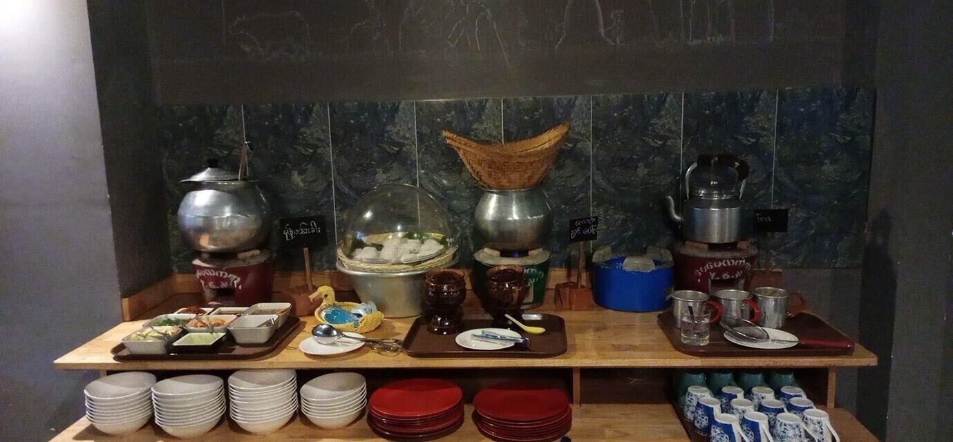 A buffet setup with various food containers, serving utensils, and stacked plates.
