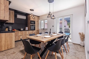 Una cocina moderna con armarios de madera, una mesa de comedor para seis personas y vistas a un balcón.