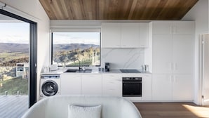 Una cocina moderna con un amplio ventanal, electrodomésticos integrados y techo de madera.