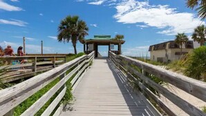 A wooden boardwalk leading to a gazebo with a green roof, surrounded by palm trees and a clear sky. - CUTE! little end-unit beach townhome (Panama City Beach)