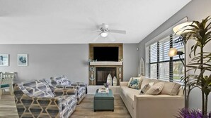 A living room with a fireplace, two sofas, a coffee table, and a ceiling fan. - CUTE! little end-unit beach townhome (Panama City Beach)
