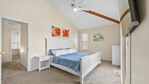 A bedroom with a white bed, a nightstand, a ceiling fan, and artwork on the walls. - CUTE! little end-unit beach townhome (Panama City Beach)
