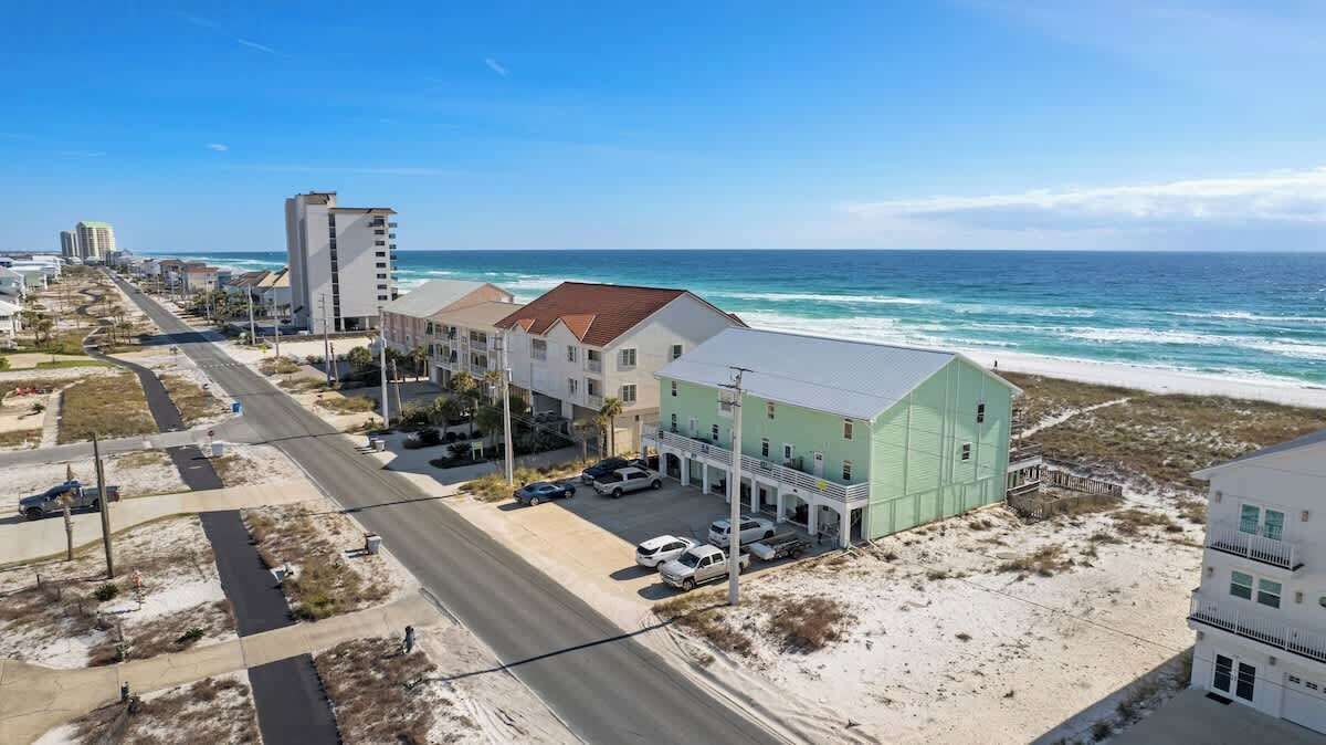 Un hôtel situé sur la côte, doté d’un parking, offrant une vue sur la plage et donnant accès à une route menant à l’océan.