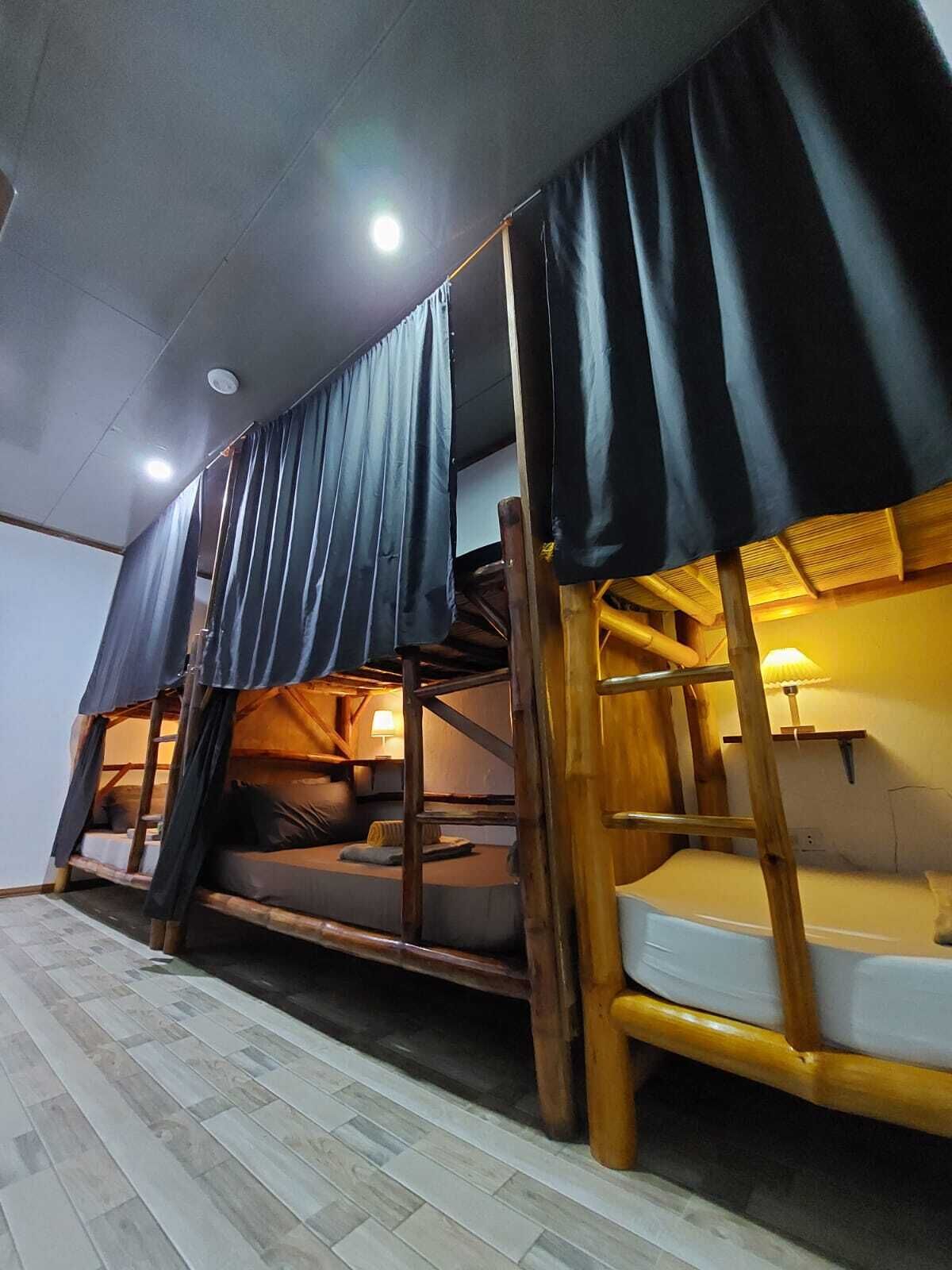 A room with bunk beds, wooden beams, and a tiled floor.