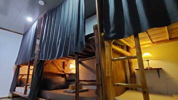 A room with bunk beds, wooden beams, and a tiled floor.