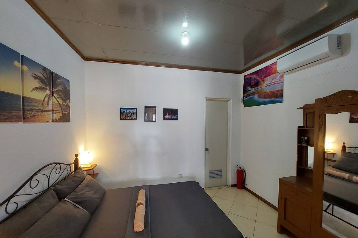 A room with a bed, a sofa, a wall-mounted air conditioner, and a door.