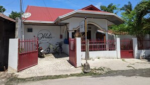 Un hostal con techo rojo y paredes blancas, que presenta un cartel y una bicicleta estacionada afuera.