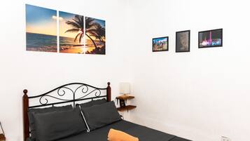 A bedroom with a bed, pillows, a nightstand, and wall art including a sunset and cityscape.