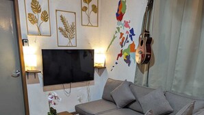Una sala de estar moderna con un sofá modular, un televisor de pantalla plana montado en la pared, una guitarra y decoración en la pared.