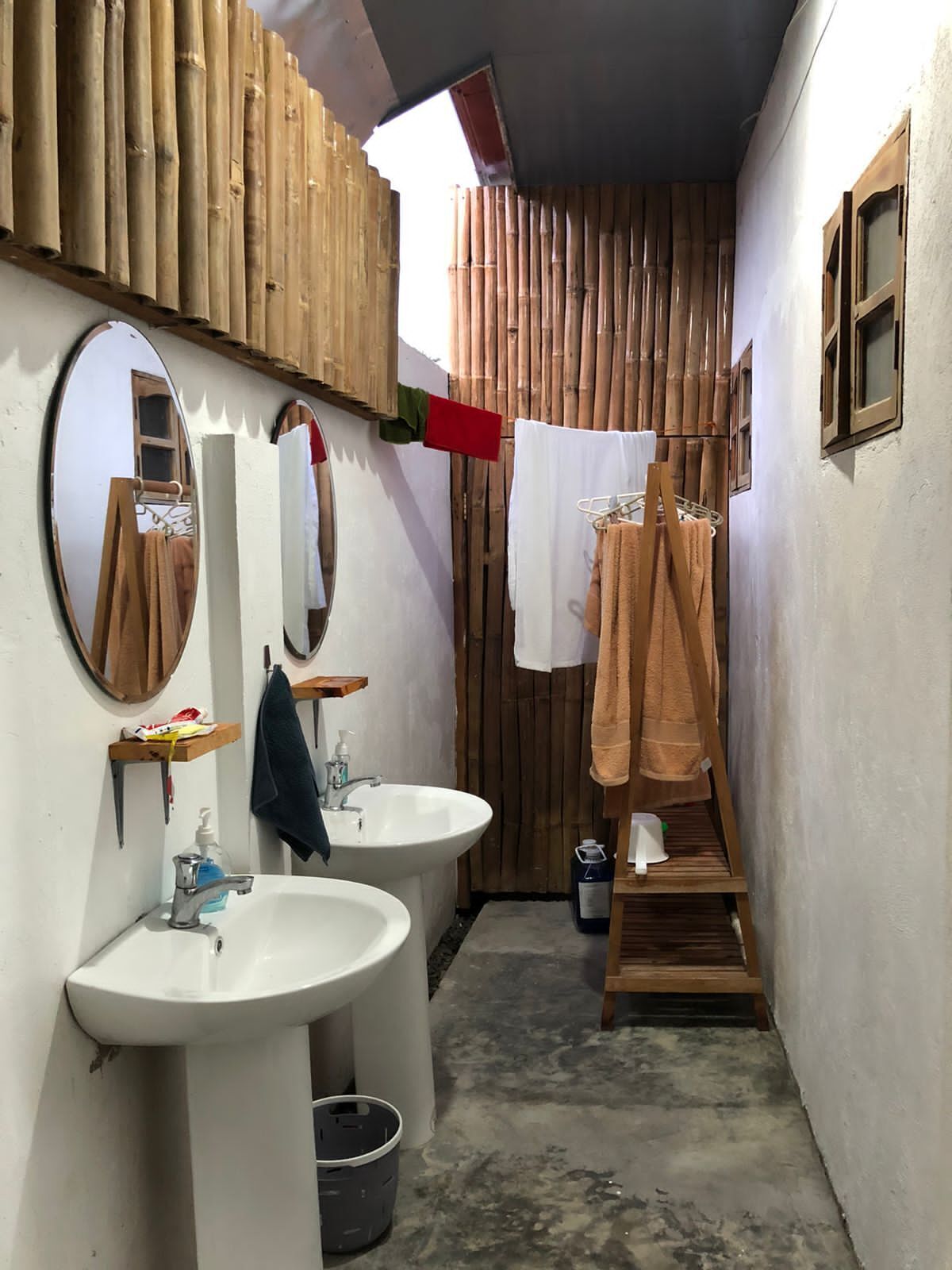 Un baño con dos lavamanos, un espejo y un toallero de madera.