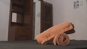 A room with a wooden door, a mirror, and a rolled-up towel on a dark surface.
