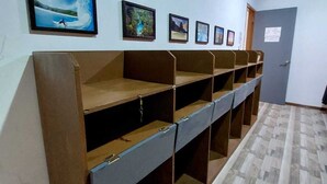 Una habitación con una larga hilera de bancos de madera a lo largo de una pared, suelo de baldosas y varias fotografías enmarcadas.