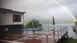 A building with a balcony overlooking a body of water, a trampoline, and a flag. - The NIhal Resort (Mahabaleshwar)