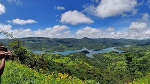 A panoramic view of a lush valley with a river, surrounded by green hills and clear blue sky. - The NIhal Resort (Mahabaleshwar)