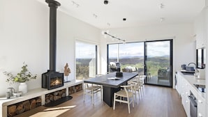 A modern kitchen with a central island, a built-in stove, and large windows offering a view of the countryside. - The Bella Vista by Mt Bellevue - with spa and spectacular views. (Myrrhee)