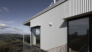 A modern building with a large window and a balcony overlooking a scenic landscape. - The Bella Vista by Mt Bellevue - with spa and spectacular views. (Myrrhee)