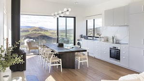 A modern kitchen with a large island, white cabinetry, and a view of rolling hills. - The Bella Vista by Mt Bellevue - with spa and spectacular views. (Myrrhee)