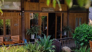 A wooden cabin named 'Desi House' with a porch, seating area, and potted plants. - Ta Van (Ta Van)