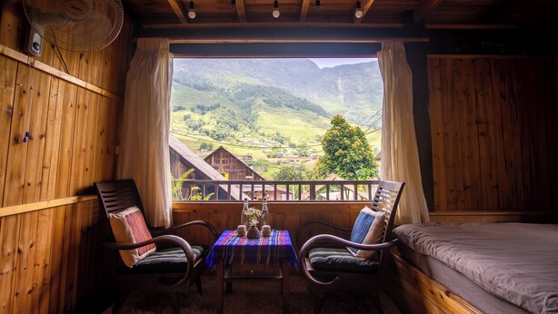 A wooden cabin room with a balcony, a table with chairs, and a bed. - Ta Van (Ta Van)