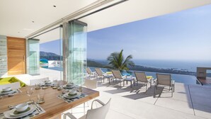 A modern dining area with a table set for four, overlooking a scenic ocean view. - Splash 4 Bed :Contemporary Tropical Five Star Villa (Koh Samui)