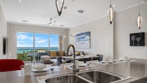 Een moderne keuken met een groot schiereiland, een roestvrijstalen spoelbak en een eethoek met uitzicht op de oceaan.