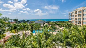 Een resort met een zwembad, palmbomen en uitzicht op de oceaan.