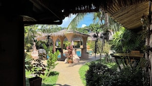 Un complexe hôtelier tropical doté d’une piscine, de bâtiments à toits de chaume et d’une végétation luxuriante.