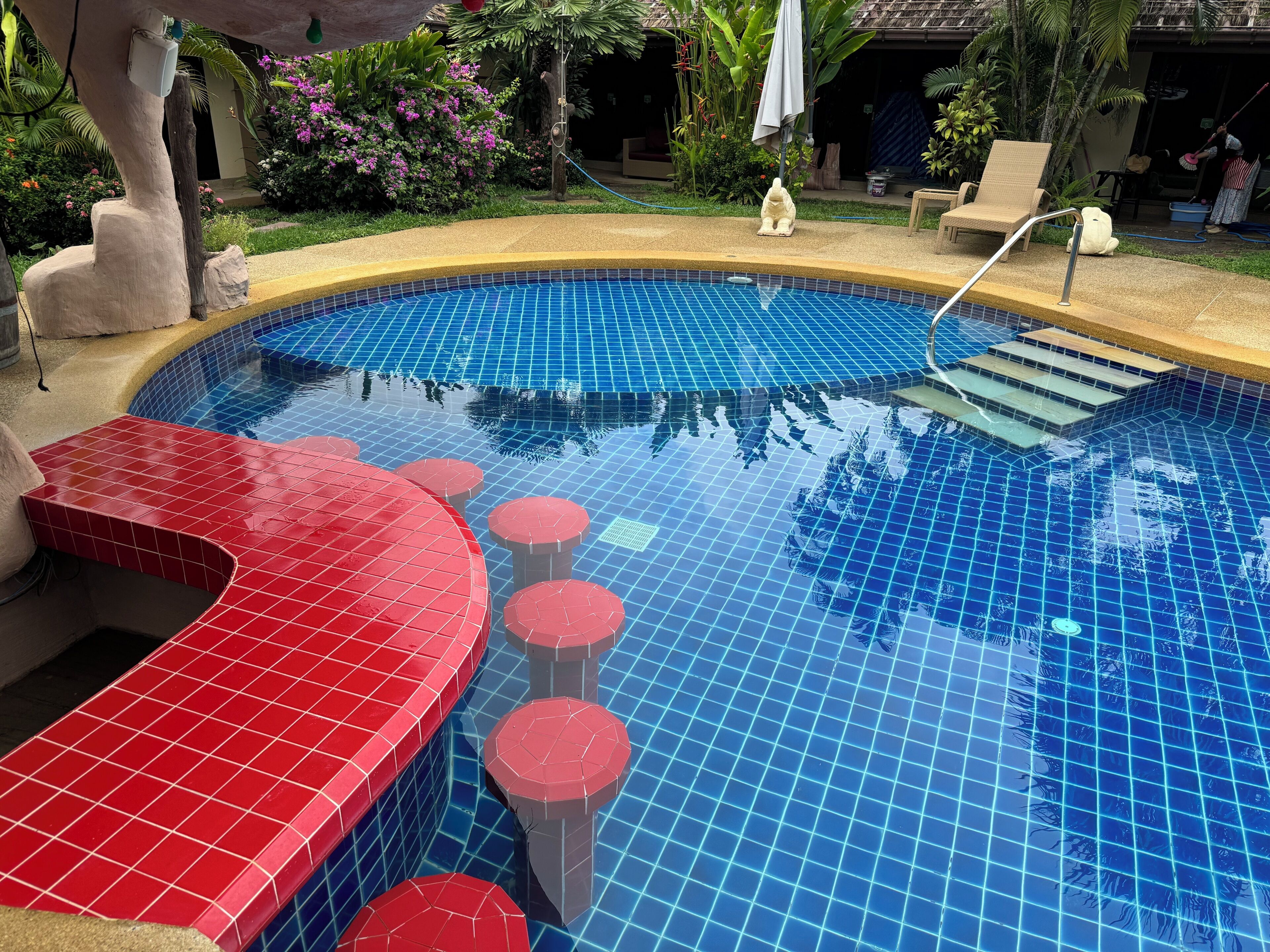Una piscina con escalones de azulejos rojos y azules y una pequeña estatua.