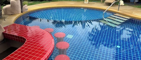 Una piscina con escalones de azulejos rojos y azules y una pequeña estatua.